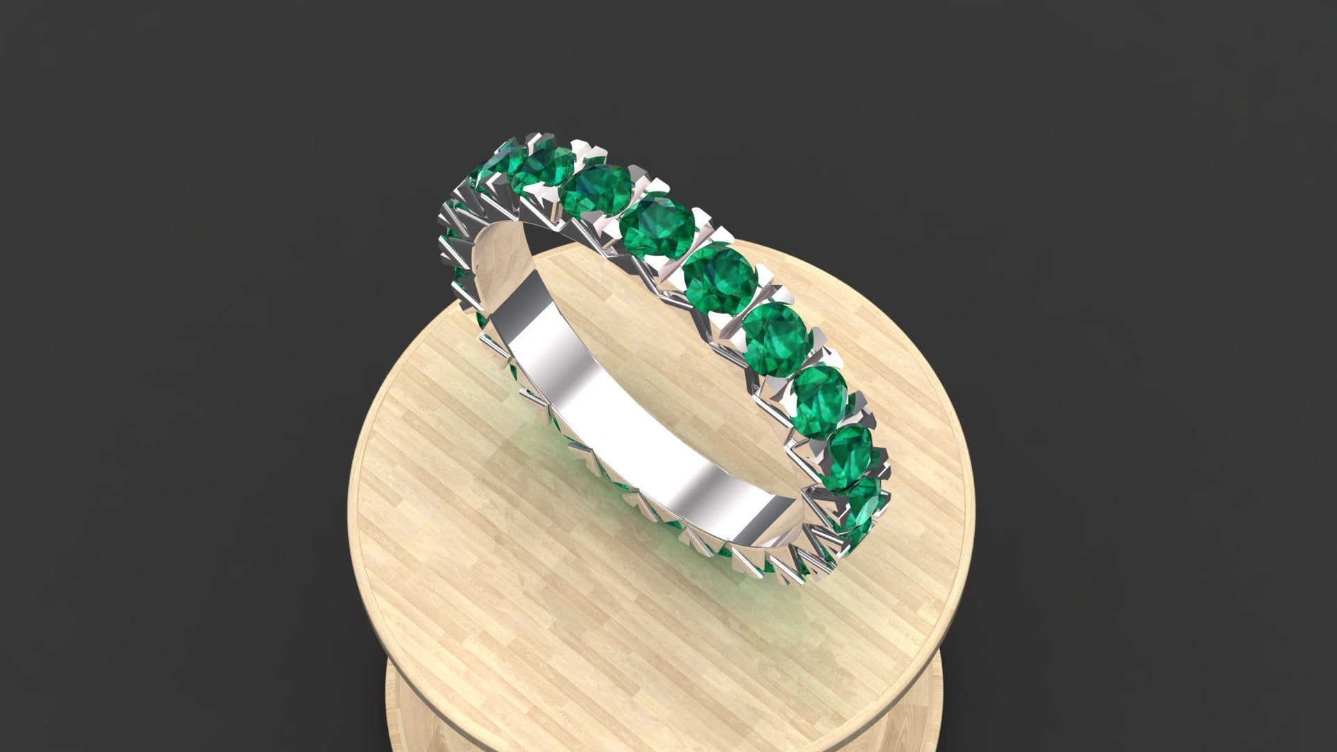 The "Elara" custom birthstone ring shown with emerald green stones in a comfortable half-eternity style.